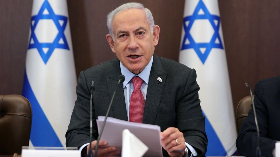 Benjamin Netanyahu hablando en una reunión con banderas de Israel.