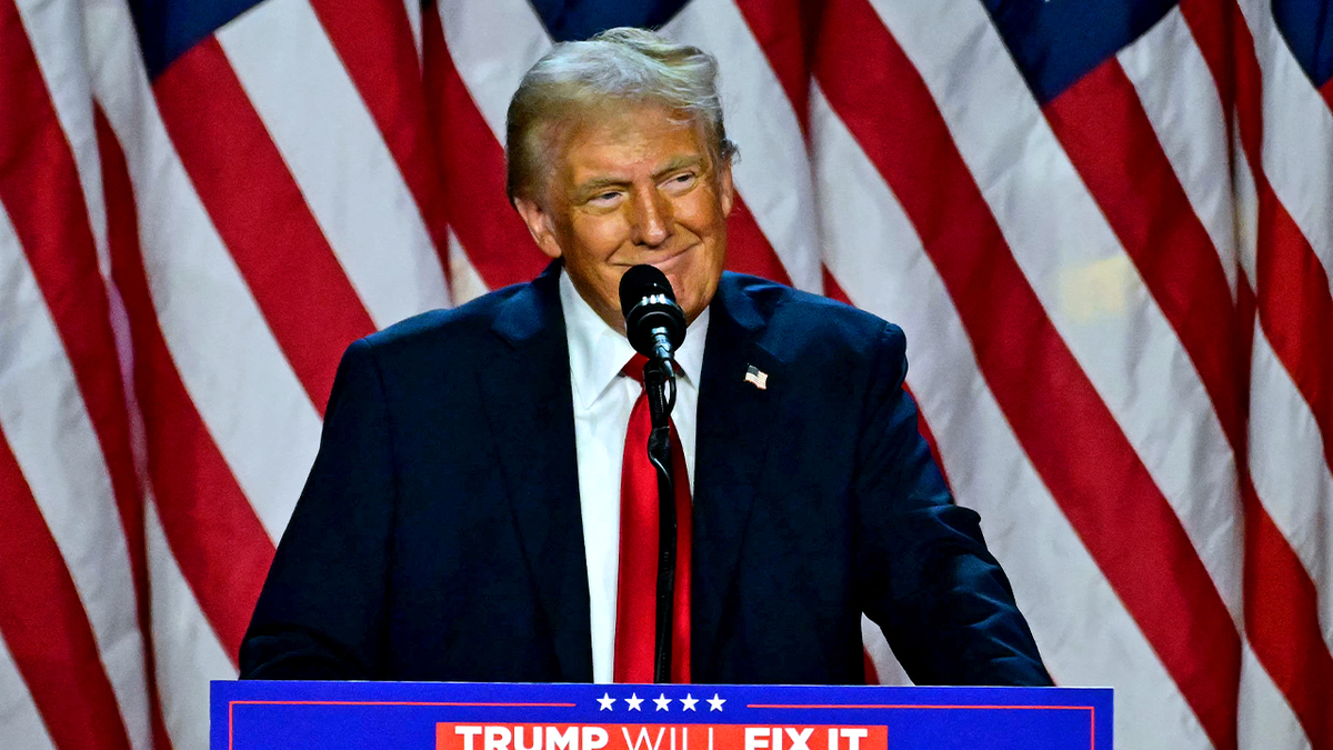 Donald Trump hablando frente a banderas estadounidenses.