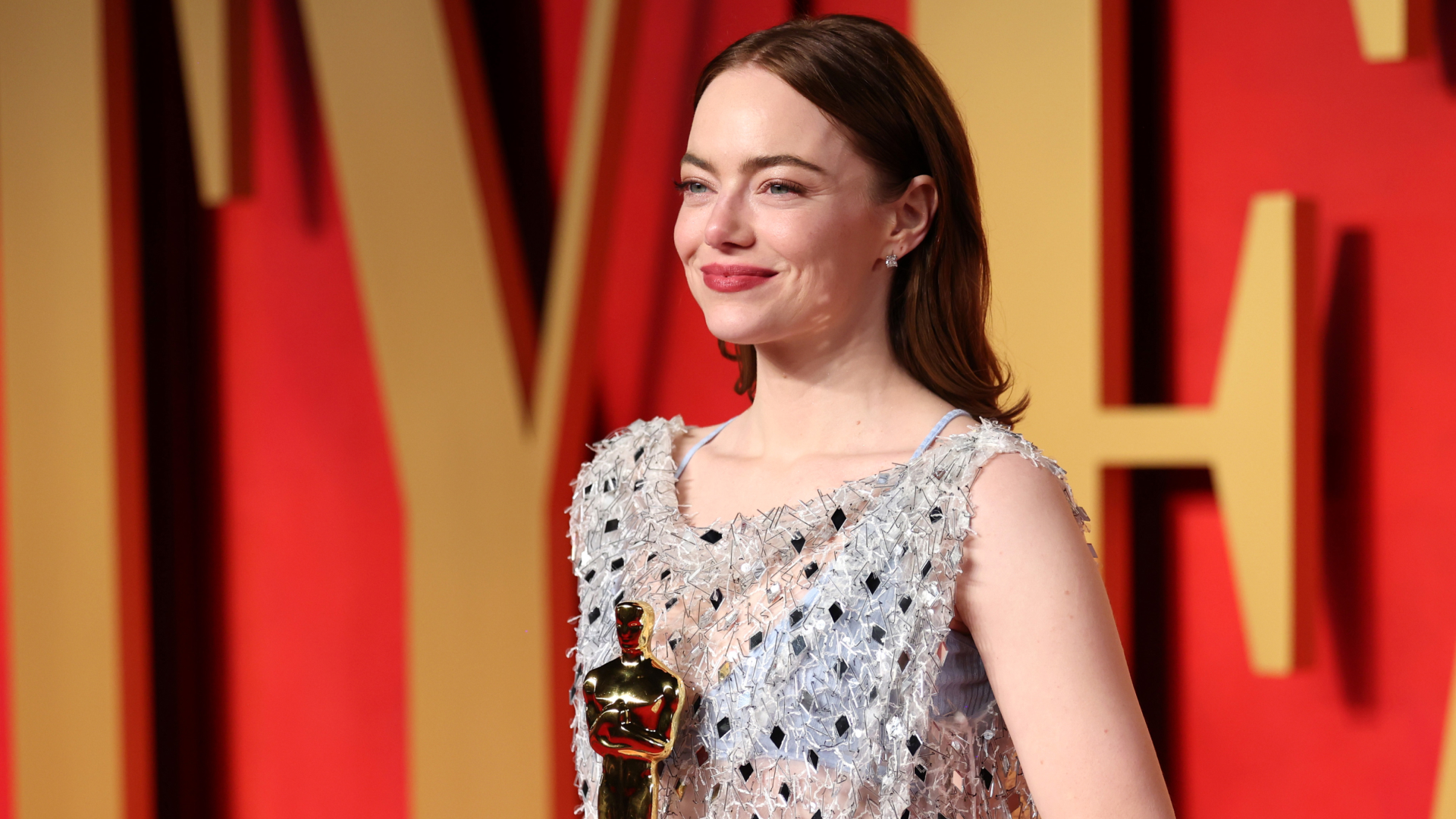 Emma Stone sonriente con un Óscar en la mano.
