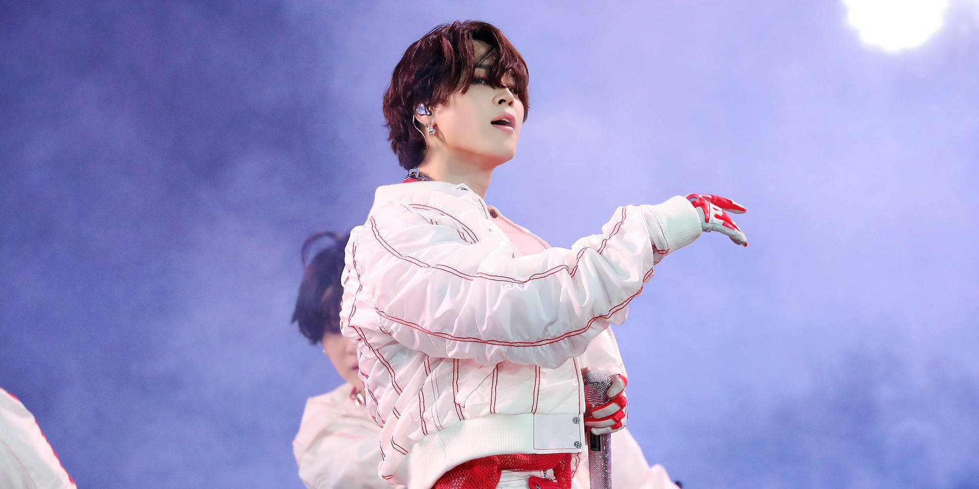 Jimin de BTS cantando y actuando en un escenario vibrante.