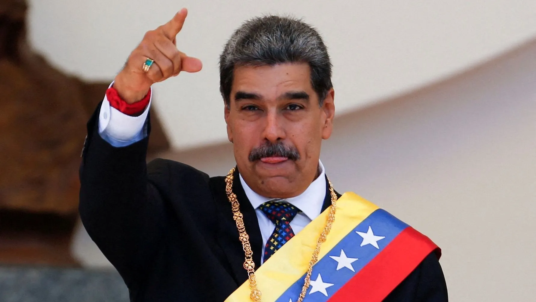 Nicolás Maduro, mandatario de Venezuela, en ceremonia con banda presidencial y gesto distintivo.