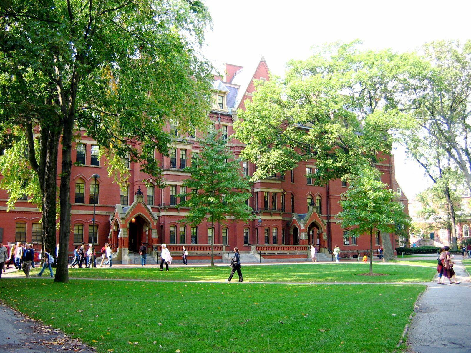 Edificio de la Universidad de Harvard rodeado de estudiantes y árboles.